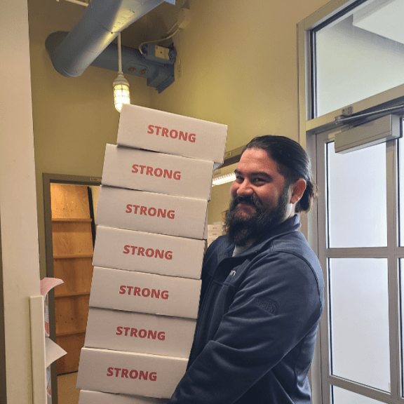 Man carrying a large stack of boxes while smiling