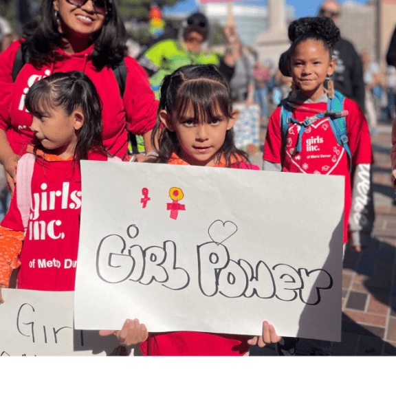 Girl holding a hand written sign that reads girl power