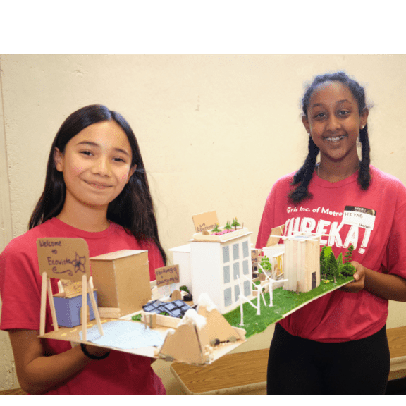 Two girls holding a 3d model of a city they built