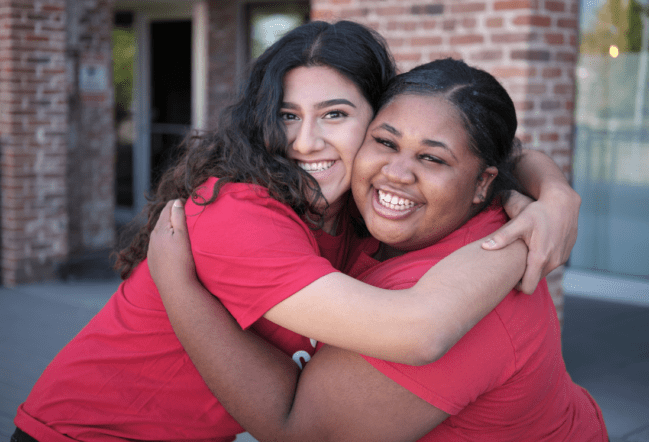 Two Girls Inc. teens hugging and smiling