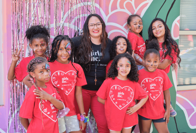 A Girls Inc. staff member posing with a group of girls smiling